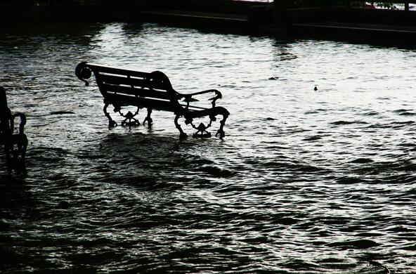 An empty bench sits in flood waters