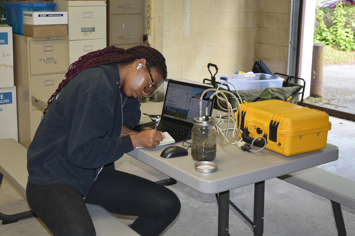 student writes at a table full of lab equipment