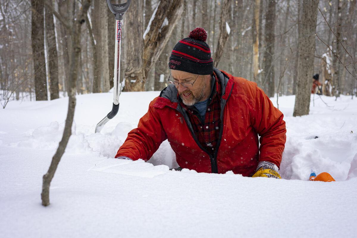 researcher digging in snow with tools around him