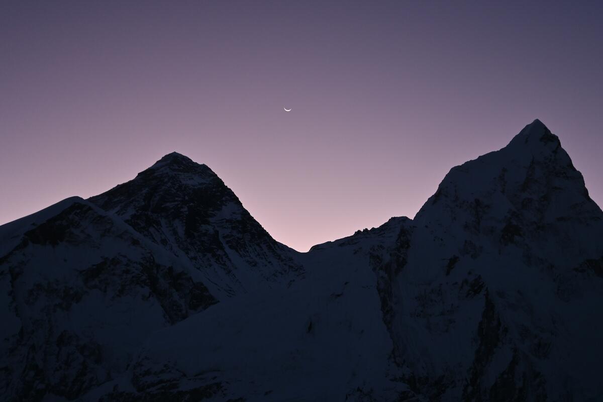 Crescent moon over Mount Everest with purple sky